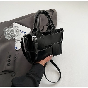 Detail of black woven bucket bag showing premium leather texture and dual handles