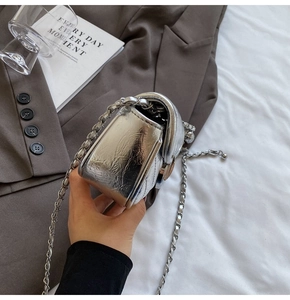 Close-up of silver pleated faux leather crossbody bag with metallic chain strap detail