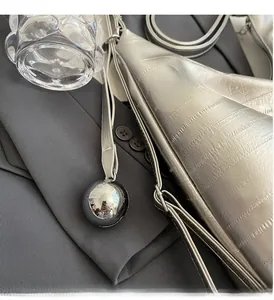 Macro detail of silver crocodile embossed tote bag with metallic sphere charm