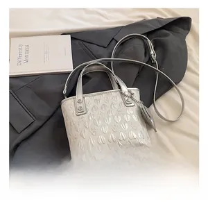 Detail of white bucket bag with silver heart embossing and metallic chain ornament