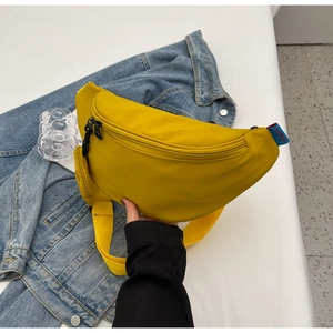 Detail of a bright yellow crescent nylon chest bag with a mini round pouch and shoulder strap