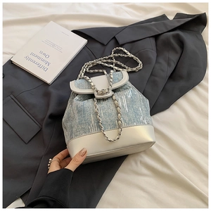 Detail of blue sequin bucket bag with silver chain strap and white leather stitching