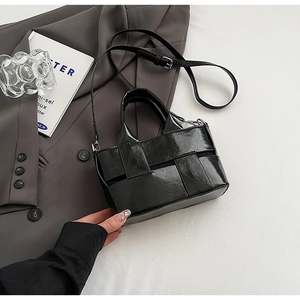 Detailed view of black woven mini bucket bag featuring high-gloss PU leather texture