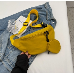 Detail of yellow canvas sling bag with small round coin purse on denim jacket