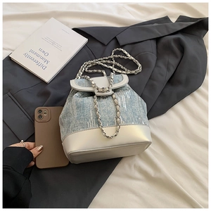Detail view of denim bucket bag with silver sequins and white leather base on a suit
