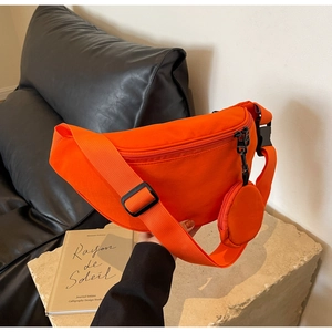 Detail of bright orange canvas crossbody bag with mini pouch and adjustable black strap