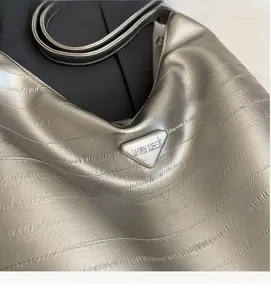 Close-up of silver tote bag with pleated texture and inverted triangle metal logo