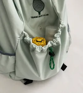 Detail of mint green backpack front pocket with elastic drawstring and logo