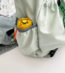 Close-up of a side mesh pocket on a green backpack holding a yellow folding umbrella