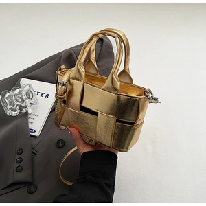 Detail of metallic gold woven bucket bag with silver buckles and adjustable strap