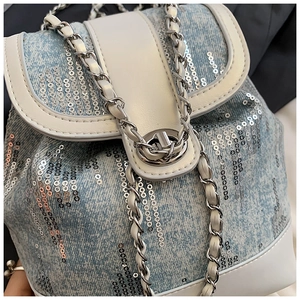 Macro detail of sequin denim backpack with silver chain strap and metal clasp