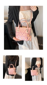 Detail of pink heart-embossed handbag with puppy charm and detachable shoulder strap
