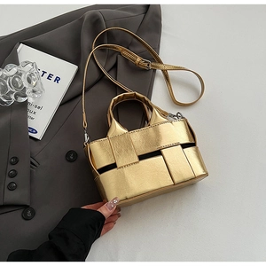 Detailed view of mini golden woven leather bucket bag on a grey blazer suit jacket