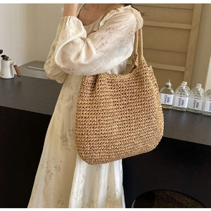 Detail of hand-woven straw tote bag with tight knit texture and matching woven shoulder strap
