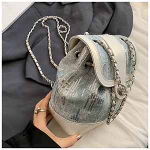 Detailed shot of a light blue sequin bucket backpack with chain strap and white leather flap