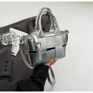 Detailed close-up of a silver woven bucket bag with metallic finish and top handles