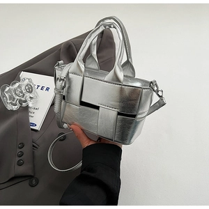 Detail of silver woven bucket bag with metallic texture and adjustable shoulder strap