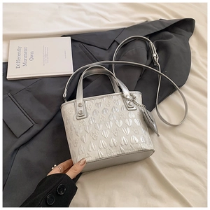 Detail of silver heart-embossed handbag with matching strap and heart charm