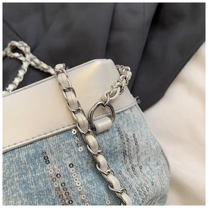Detail of light blue denim bucket bag featuring silver sequins and metal chain strap