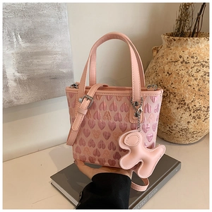 Detail of pink heart-patterned handbag with cute animal charm and leather strap