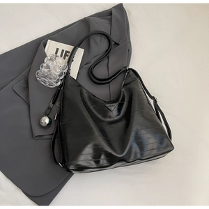 Detail of black crocodile pattern hobo bag with triangle logo and silver ball charm