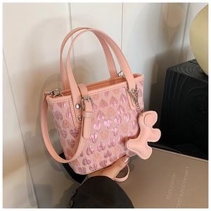 Detailed view of pink heart jacquard handbag featuring a leather bear charm and silver hardware