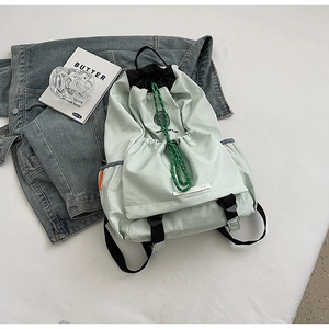Detail of light green hiking backpack with drawstring closure and athletic print