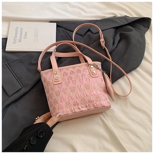 Detail of pink heart embroidery and metallic rivets on a leather handbag surface