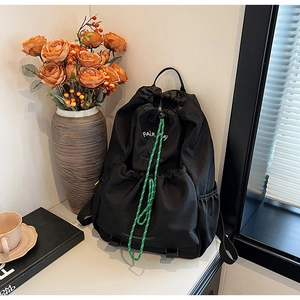 Detail of black Fairway tennis club backpack with vibrant green drawstring on white table