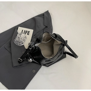 Detail of black PU leather tote bag with silver charm and functional inner lining