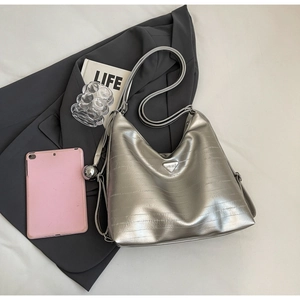 Detail of silver embossed leather hobo bag with triangle logo and ball charm accessory
