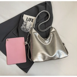 Silver hobo tote bag with metal logo and textured leather on a minimalist background