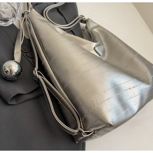 Detail of silver hobo bag with horizontal texture and triangular logo on a blazer