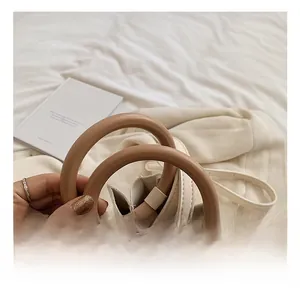Détail d'un sac plissé abricot avec une élégante poignée circulaire en résine marron