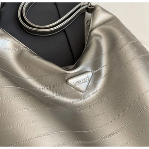 Detail of silver metallic tote bag with pleated texture and triangular logo plate