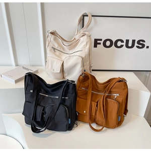 Three colors of large nylon tote bags with front pockets and smooth matte texture