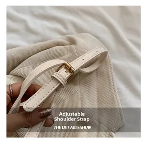 Gros plan sur la bandoulière réglable avec boucle en métal doré d'un sac seau à plis