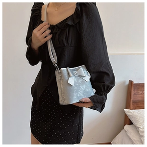 Silver mini bucket bag with large bow detail shown on shoulder for sizing and scale
