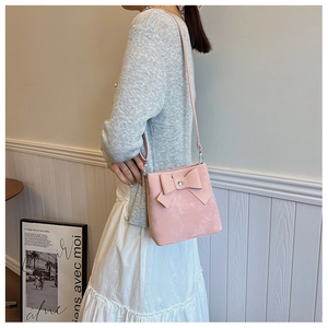 Detailed view of pink matte leather shoulder bag with a large bow and silver hardware