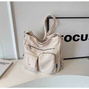 Detail view of large cream nylon tote with multiple pockets and adjustable shoulder strap