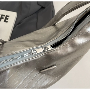 Detail of silver tote bag showing vertical pleated texture and metal zipper closure