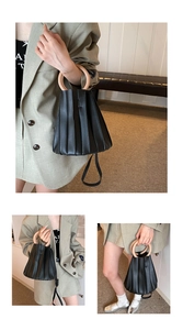Détail du sac seau plissé noir avec poignée ronde en bois et bandoulière amovible