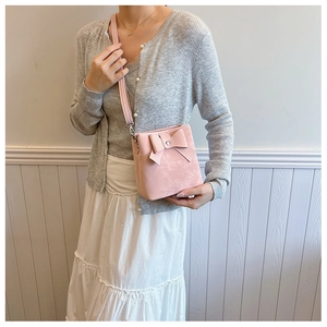 Detailed close-up of a pink bucket bag featuring a large bow and soft matte texture