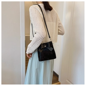 Detail of black bow-knot shoulder bag with matte finish shown on model's shoulder