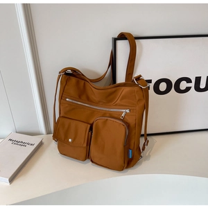 Detailed side view of caramel nylon backpack with metallic zippers and multi-pocket layout