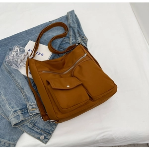 Detailed view of brown nylon crossbody bag with multiple zip pockets and adjustable strap