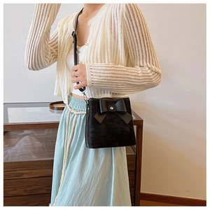 Black leather bucket bag with bow detail worn by model showing size and styling