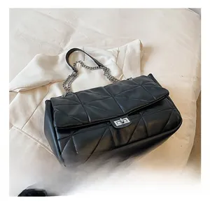 Detail of black quilted shoulder bag with silver chain strap and metal turn-lock closure