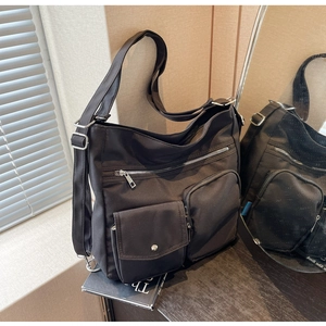 Detail of black nylon messenger bag with multiple zipper pockets and adjustable strap