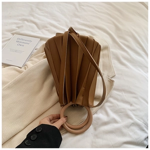 Détail du sac plissé à poignée anneau posé sur une veste de blazer beige clair